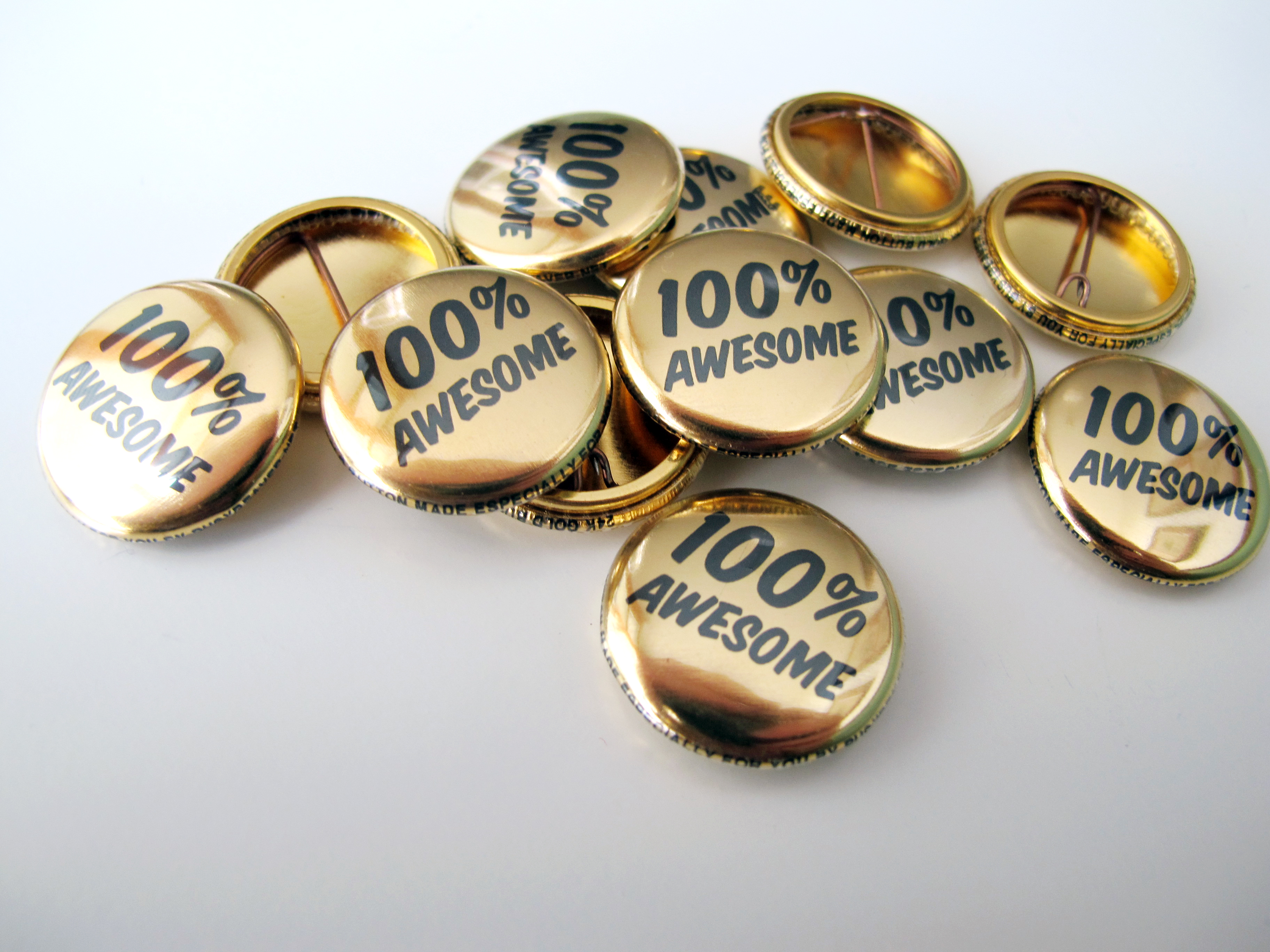 a pile of 24k gold buttons that say 100%