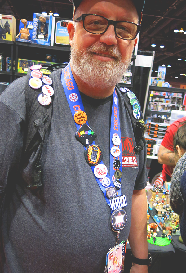 man wearing comic con buttons on backpack